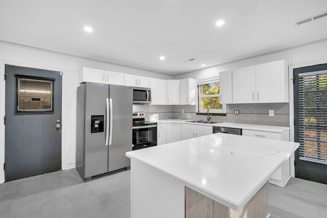 kitchen featuring white cabinets, visible vents, a sink, tasteful backsplash, and appliances with stainless steel finishes