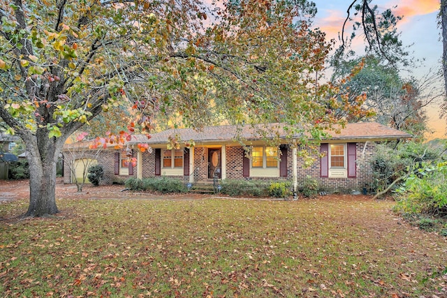 ranch-style house with brick siding, a yard, and a porch