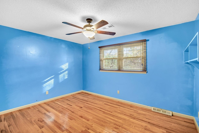 empty room featuring baseboards, a ceiling fan, wood finished floors, and visible vents