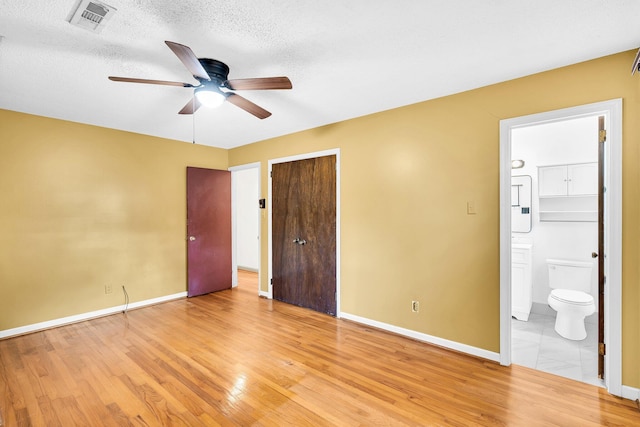 unfurnished bedroom featuring visible vents, ensuite bath, a closet, baseboards, and light wood-style flooring