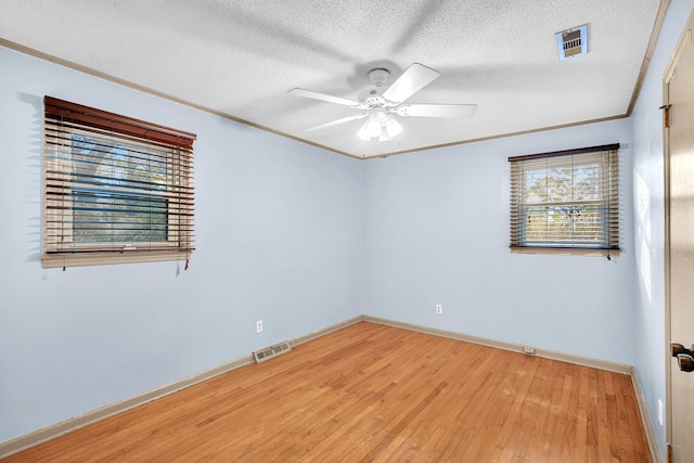 empty room featuring light wood-style floors, visible vents, a textured ceiling, and ceiling fan