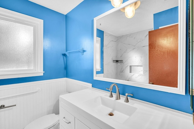 bathroom featuring wainscoting, toilet, and vanity