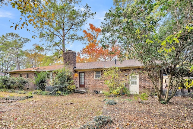 rear view of house with a chimney, brick siding, and entry steps