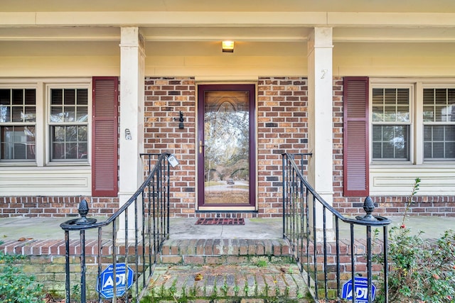 doorway to property with brick siding and a porch