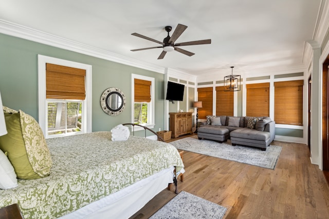 bedroom with ceiling fan with notable chandelier, crown molding, and light wood-type flooring