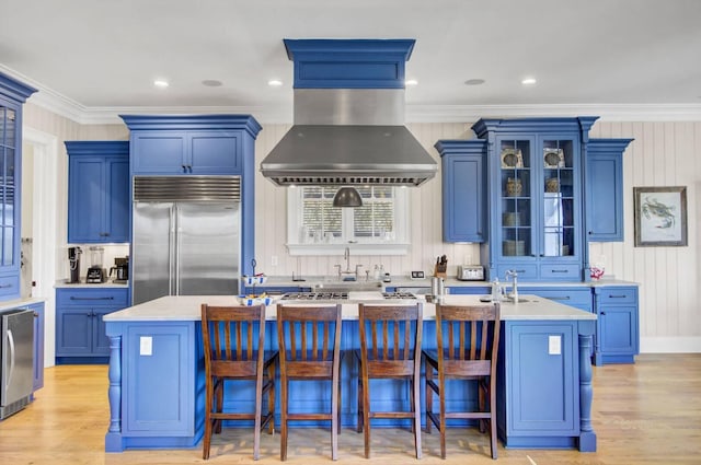 kitchen featuring stainless steel built in refrigerator, island exhaust hood, a kitchen island with sink, and a kitchen bar