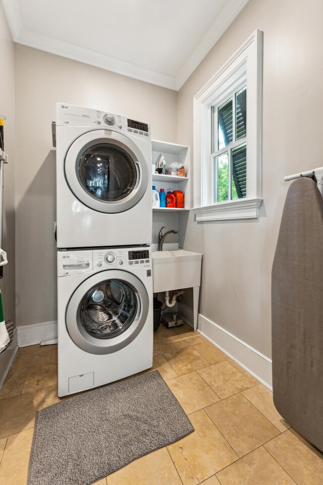 laundry area featuring ornamental molding, stacked washer / dryer, and light tile floors