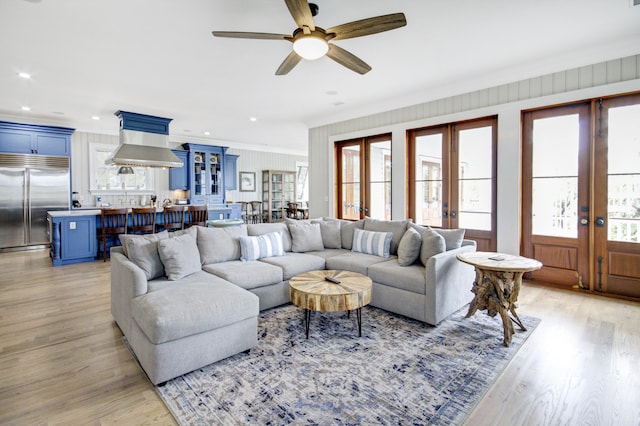 living room with french doors, ceiling fan, light wood-type flooring, and ornamental molding