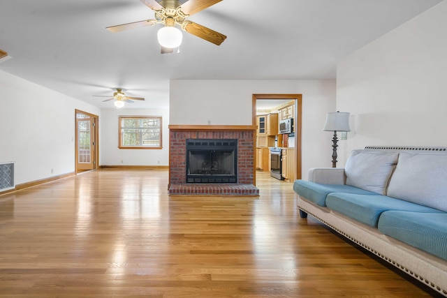 living area with a brick fireplace, light wood-style flooring, visible vents, and baseboards