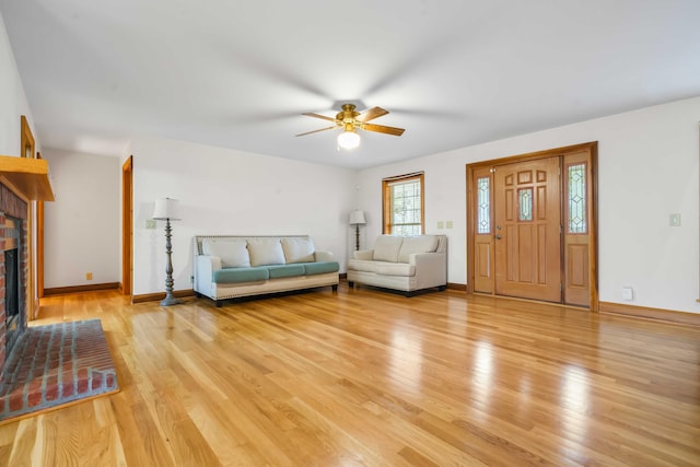 unfurnished living room featuring light wood finished floors, a fireplace, a ceiling fan, and baseboards