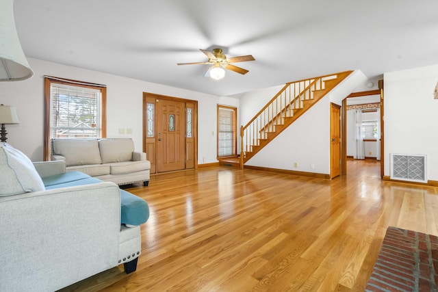 living area with a ceiling fan, baseboards, visible vents, light wood-style flooring, and stairs