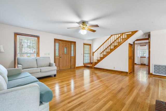 living area with stairway, light wood-style floors, visible vents, and baseboards