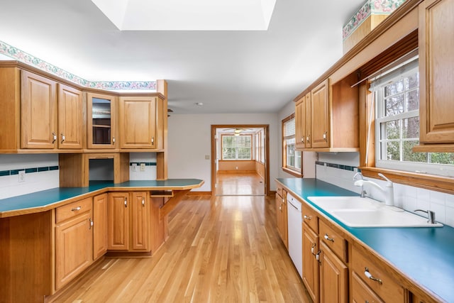 kitchen featuring a skylight, light wood-style flooring, a sink, glass insert cabinets, and dishwasher