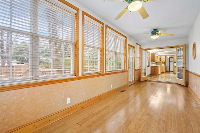 unfurnished sunroom with a ceiling fan and visible vents