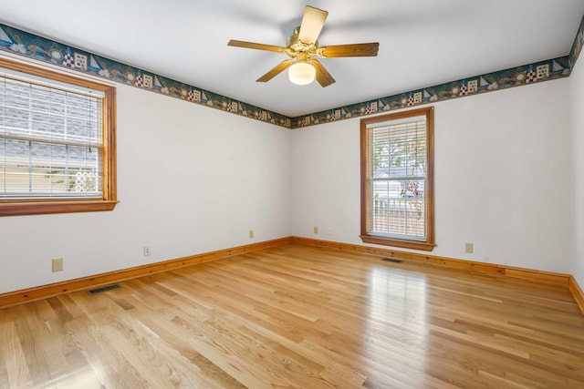 unfurnished room featuring visible vents, baseboards, and wood finished floors