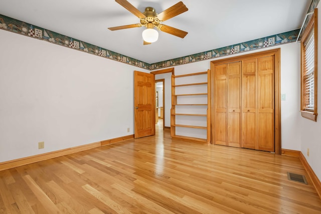 unfurnished bedroom with visible vents, light wood-style flooring, a ceiling fan, and baseboards