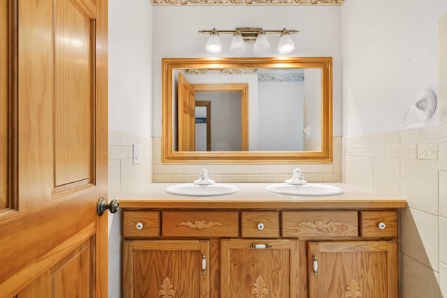 full bath featuring double vanity, tile walls, and a sink