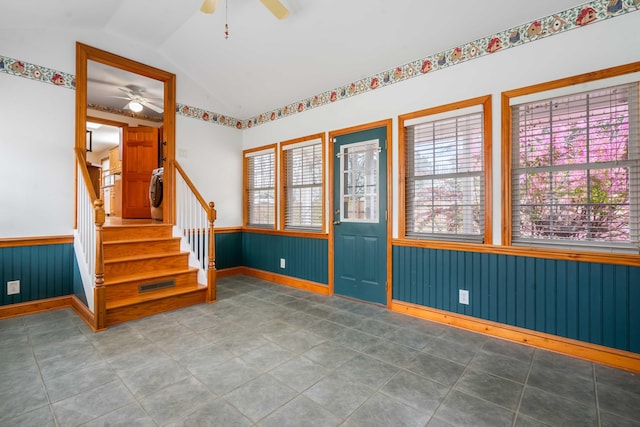 unfurnished room featuring a healthy amount of sunlight, wainscoting, stairs, and vaulted ceiling