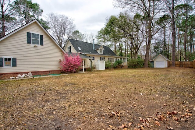 view of yard featuring an outdoor structure, fence, and a detached garage