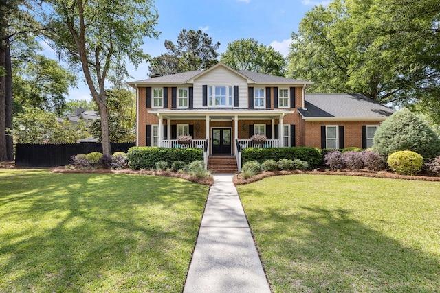 colonial-style house featuring brick siding, french doors, a front yard, and a porch