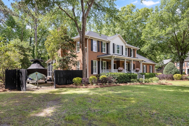 view of front of property with covered porch, brick siding, fence, and a front lawn
