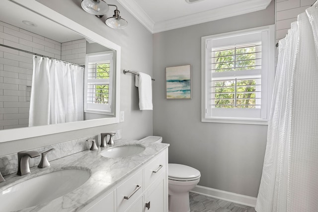 full bathroom with a sink, double vanity, toilet, baseboards, and ornamental molding