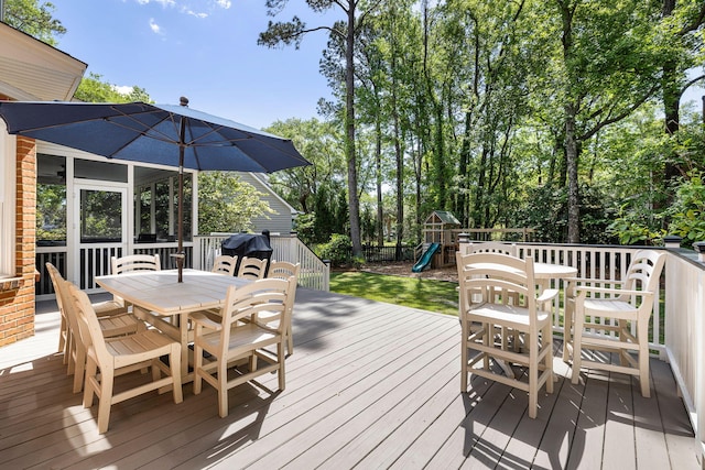 wooden deck featuring a playground, fence, and outdoor dining space