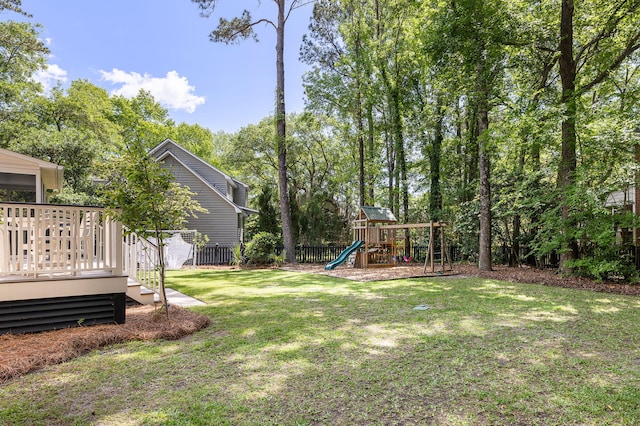 view of yard featuring a playground, fence, and a wooden deck
