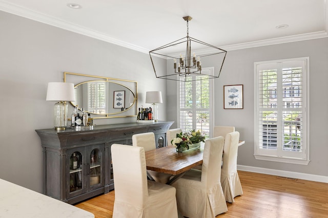dining area featuring crown molding, baseboards, light wood-style floors, and a chandelier