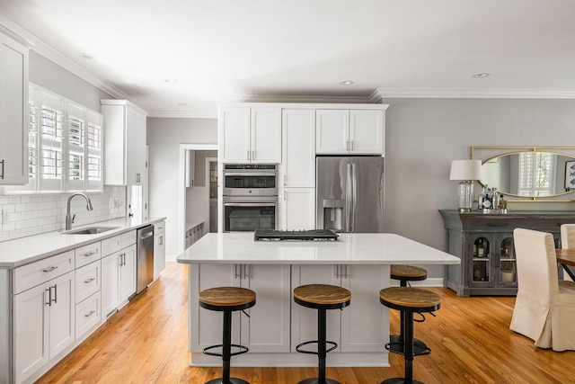 kitchen with a sink, tasteful backsplash, stainless steel appliances, and white cabinetry