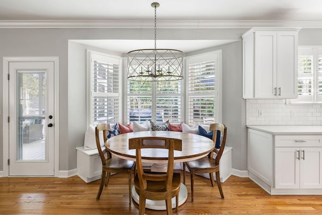 dining area featuring baseboards, ornamental molding, light wood-style flooring, and a chandelier