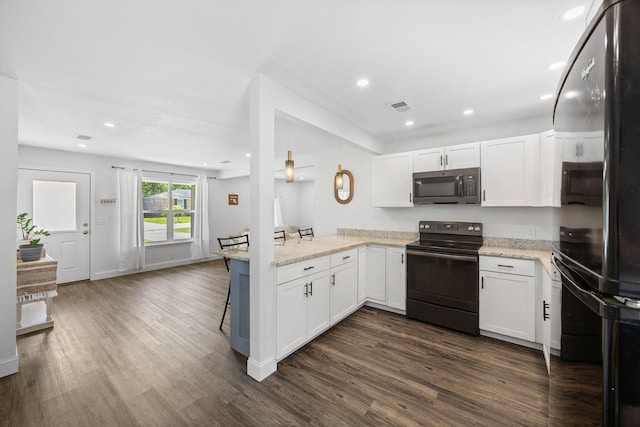 8767 Auburn Dr, North Charleston, SC 29406 - kitchen featuring black appliances, a peninsula, dark wood-type flooring, white cabinetry, and light stone countertops
