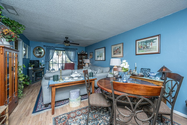 dining space featuring ceiling fan, wood-type flooring, and a textured ceiling