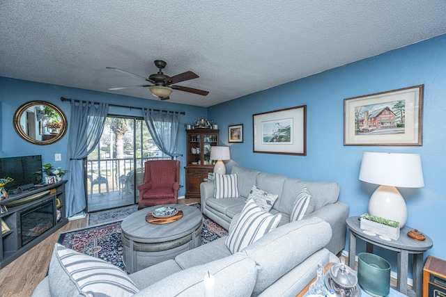 living room with ceiling fan, wood-type flooring, and a textured ceiling