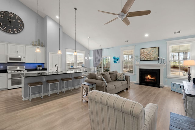 living room with light wood-type flooring, plenty of natural light, a fireplace with flush hearth, and visible vents