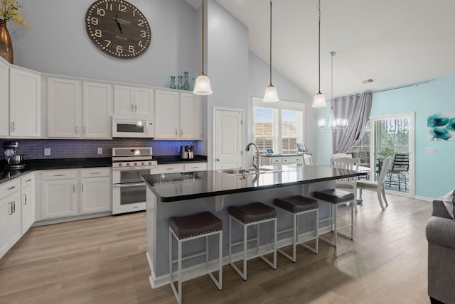 kitchen featuring dark countertops, white microwave, light wood-style floors, double oven range, and a sink