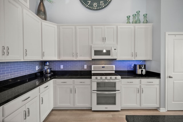 kitchen featuring white microwave, double oven range, white cabinets, and light wood-style flooring