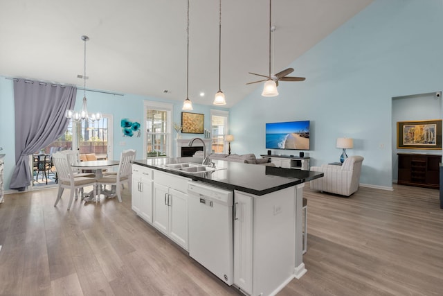 kitchen featuring light wood finished floors, dark countertops, open floor plan, a sink, and dishwasher