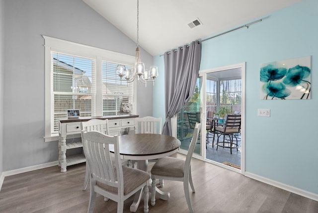 dining space with lofted ceiling, a notable chandelier, wood finished floors, visible vents, and baseboards