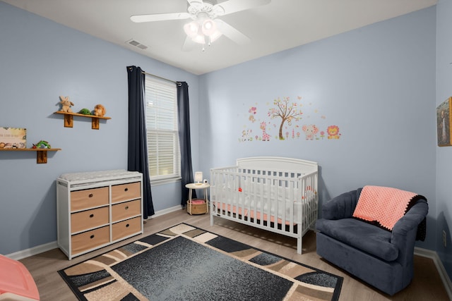 bedroom with a ceiling fan, wood finished floors, visible vents, and baseboards