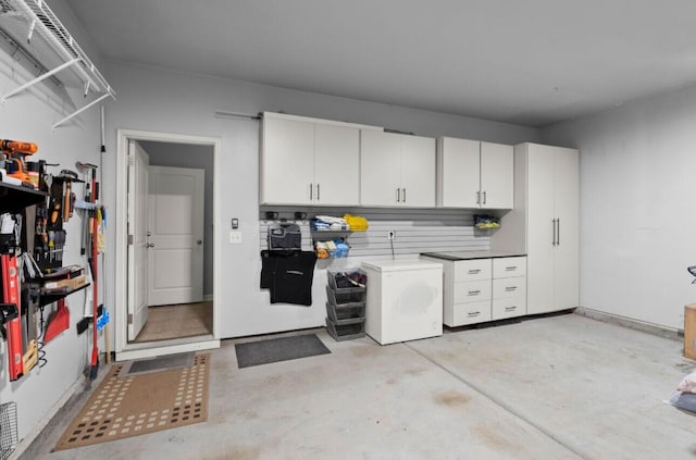 kitchen with concrete flooring, white cabinetry, and refrigerator