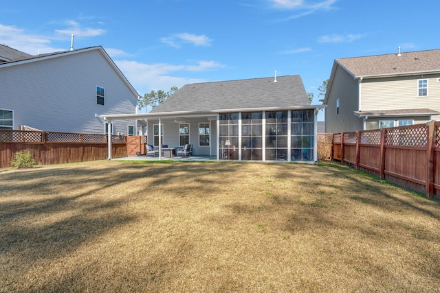 rear view of house with a sunroom, a patio area, a yard, and a fenced backyard