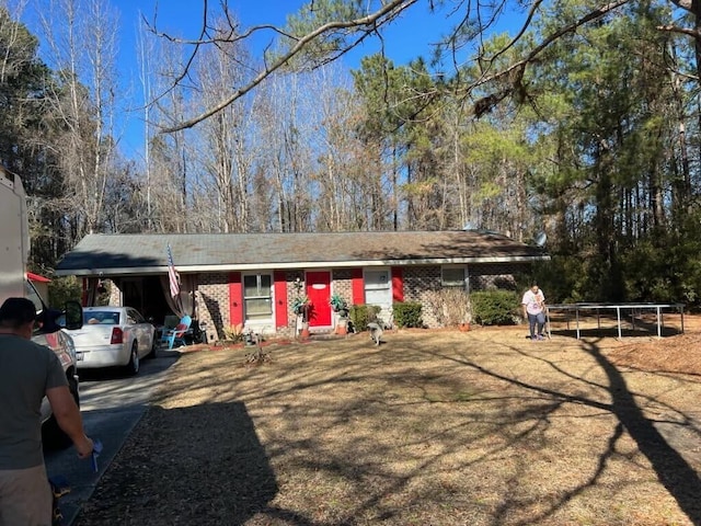 ranch-style home featuring a carport, concrete driveway, and brick siding