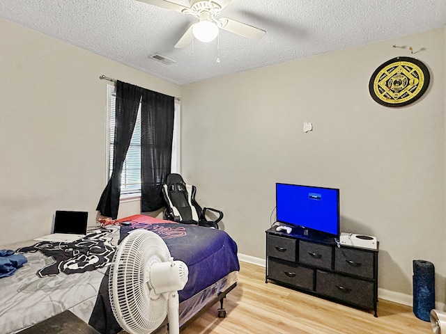 bedroom with ceiling fan, light hardwood / wood-style flooring, and a textured ceiling