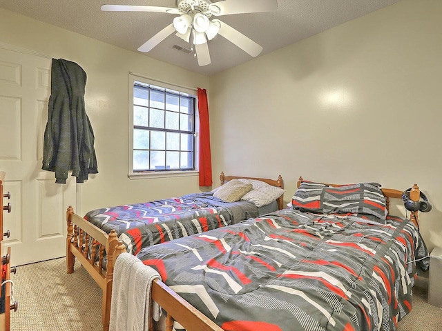 bedroom with a textured ceiling, carpet flooring, and ceiling fan