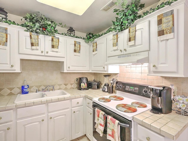 kitchen featuring white electric range oven, white cabinets, and tile counters