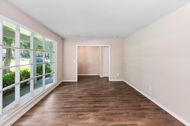 unfurnished room featuring dark wood-style flooring and baseboards