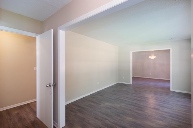 unfurnished room with baseboards, dark wood finished floors, and a textured ceiling