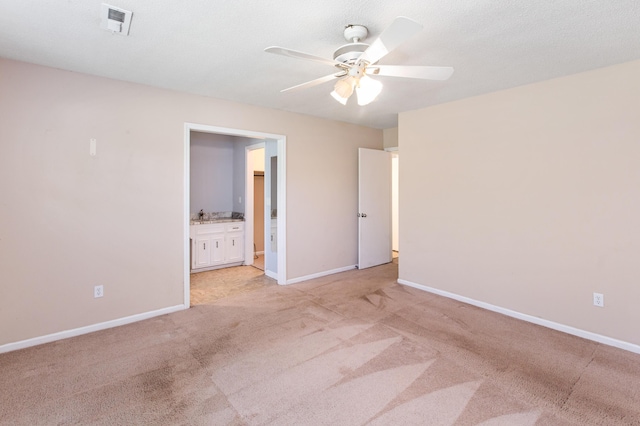 unfurnished bedroom featuring connected bathroom, light colored carpet, a ceiling fan, baseboards, and visible vents