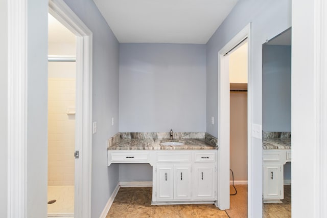 bathroom with baseboards, vanity, and a shower stall